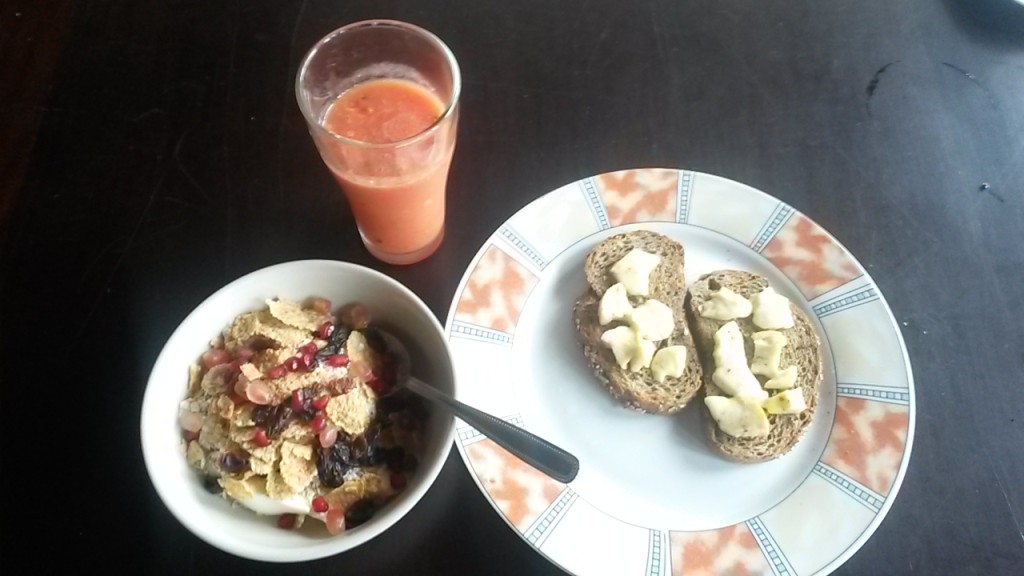 A simple breakfast at home - yogurth with muesli, toested bread with cheese and freshly made watermelon-papaya juice